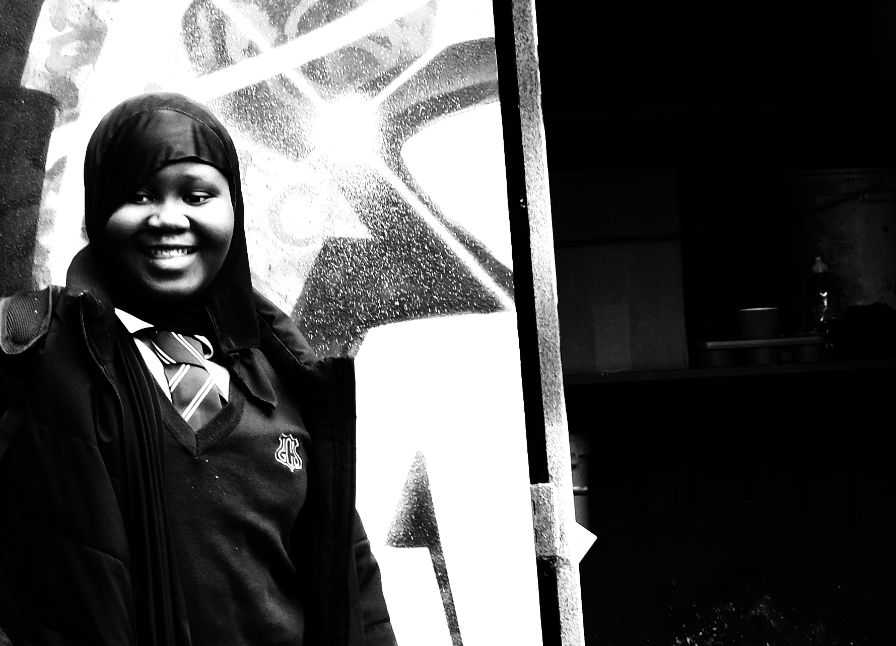 A Gladesmore student smiling in front of a graffiti wall.